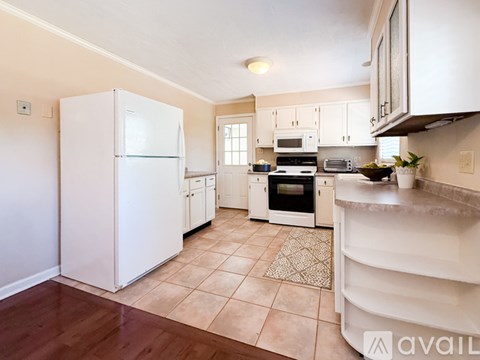 A kitchen with white appliances and wooden floors.