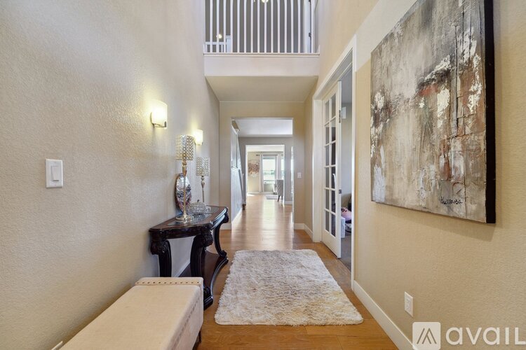 A hallway with a rug on the floor and a painting on the wall.