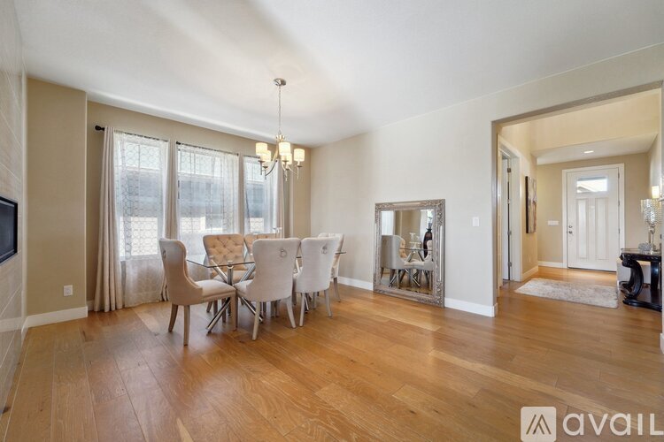 A dining room with a wooden floor and a white table set for six.