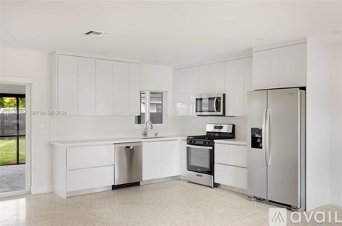 A kitchen with white cabinets and appliances.