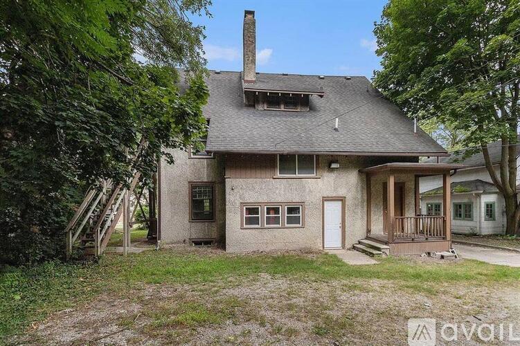 A house with a chimney and a porch is surrounded by trees.