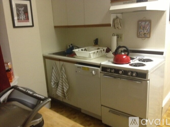 A kitchen with a white oven and a red kettle on the stove.