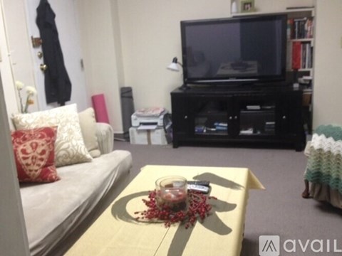 A living room with a white couch, a coffee table with a candle, and a television.