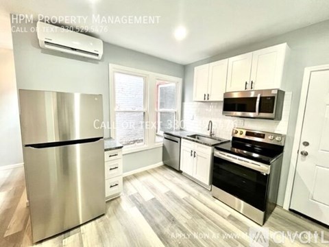 A kitchen with a stainless steel refrigerator and white cabinets.
