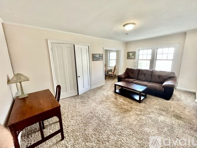 A living room with a brown couch, a wooden table, and a lamp.