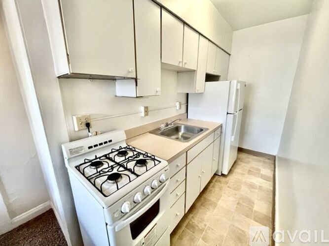 A white gas stove with a sink and a refrigerator in a small kitchen.