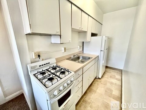 A white gas stove with a sink and a refrigerator in a small kitchen.