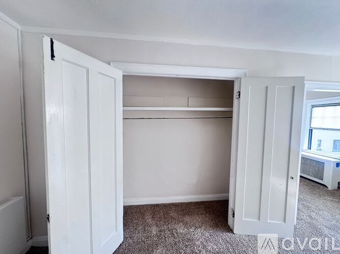 A white closet with shelves and a carpeted floor.