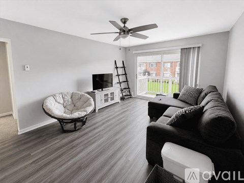 A living room with a black couch and a white chair.