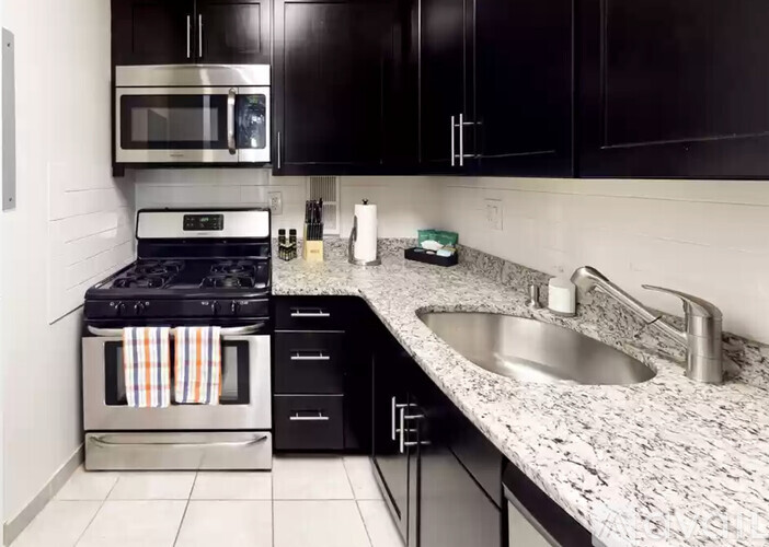 A kitchen with black cabinets and a granite countertop.
