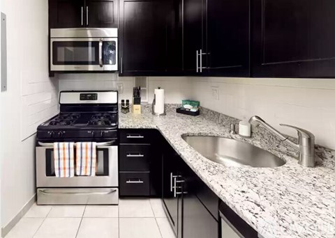 A kitchen with black cabinets and a granite countertop.