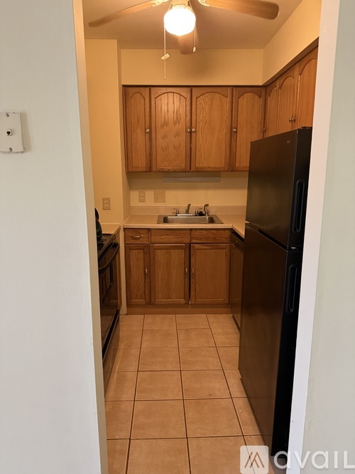 A kitchen with wooden cabinets and a black refrigerator.