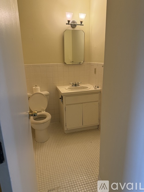 A bathroom with a toilet, sink and mirror.