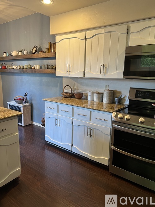 A kitchen with white cabinets and a granite countertop.