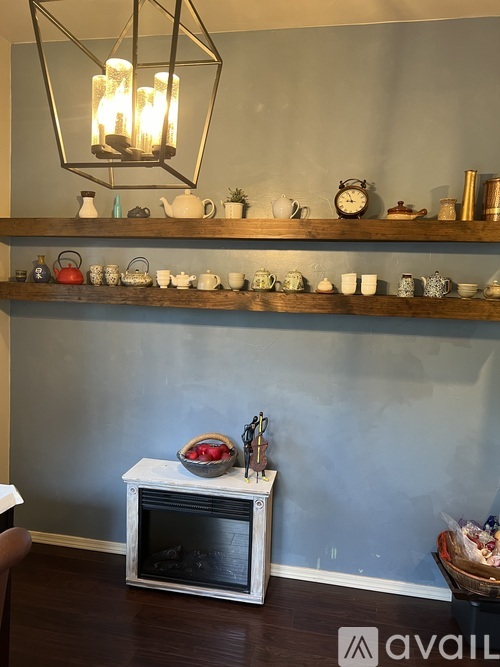 A room with a grey wall and a shelf with various items on it.