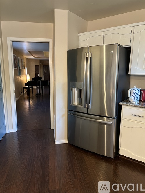 A kitchen with a stainless steel refrigerator and white cabinets.