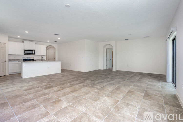 A spacious empty room with tiled flooring and white walls.