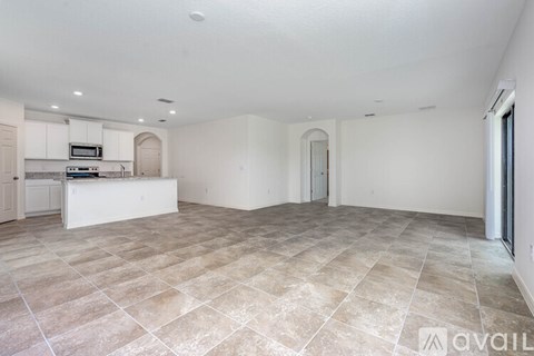 A spacious empty room with tiled flooring and white walls.