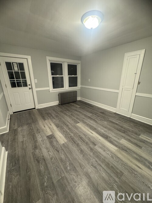 A room with grey wooden flooring and white walls.