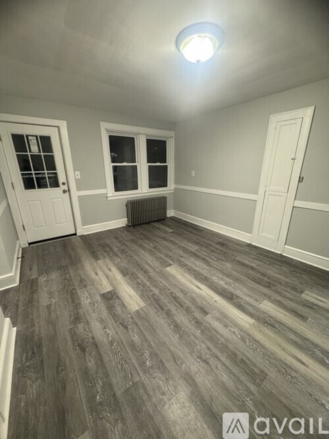 A room with grey wooden flooring and white walls.