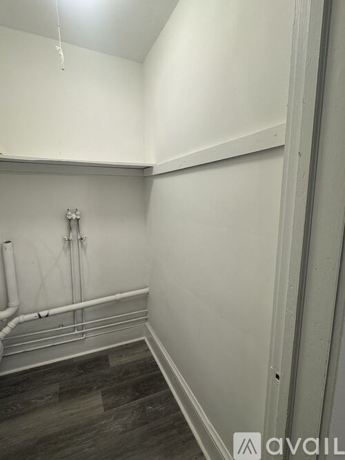 A room with white walls and a pipe on the wall.