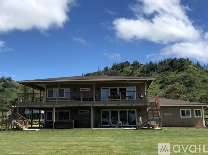 A large house with a balcony overlooking a green hill.