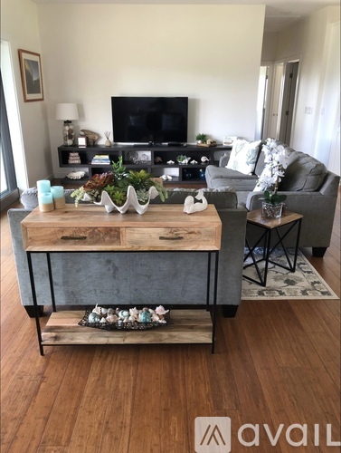 A living room with a television, grey couch, and a wooden coffee table.