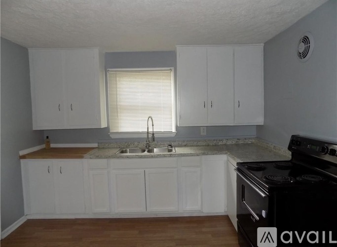 A kitchen with white cabinets and a black stove top oven.