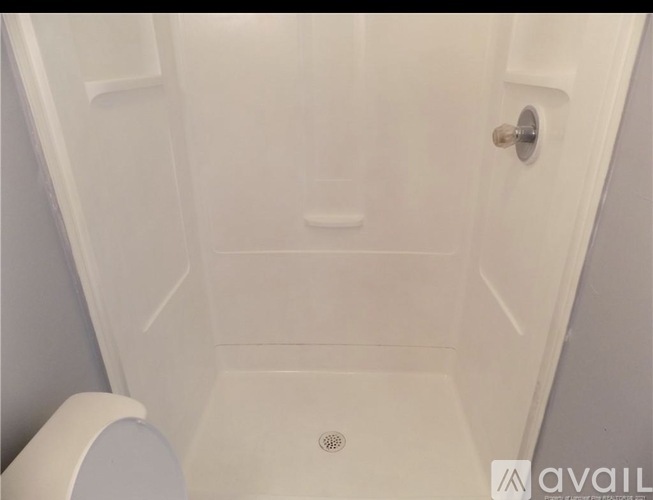 A white toilet is next to a white shower stall.