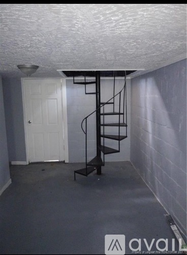 A small room with a white door and a metal staircase.