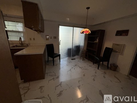 A kitchen with a marble floor and a dining area with a table and chairs.