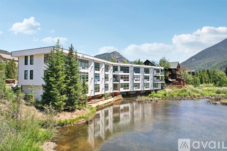 A modern building with a glass facade is situated by a river.