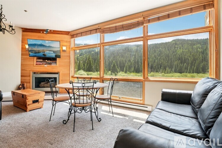 A living room with a fireplace and a view of a forest.
