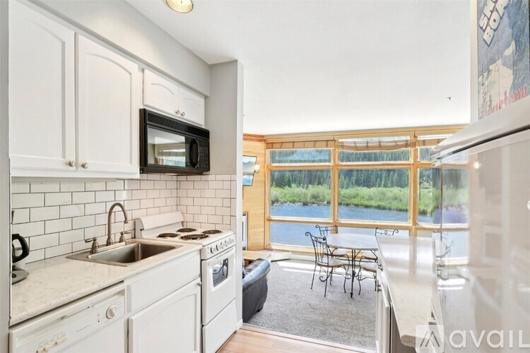 A kitchen with white cabinets and a black microwave.
