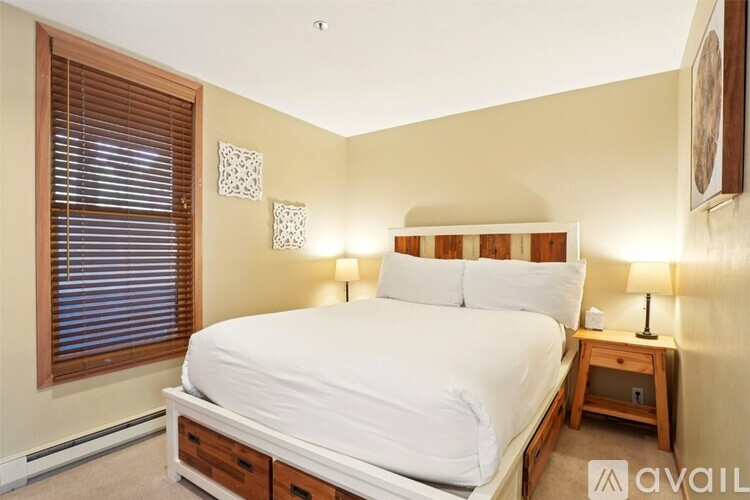 A bedroom with a white bed and wooden nightstand.