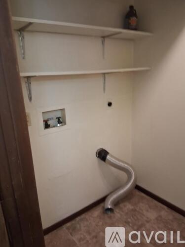A wall with a picture and a bottle on top of a shelf.