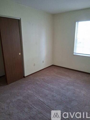 A room with a carpeted floor, a door, and a window.