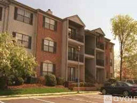 A black car is parked in front of a brick apartment building.