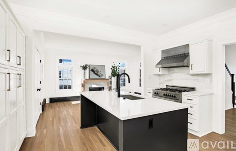 A modern kitchen with white cabinets and a black island.