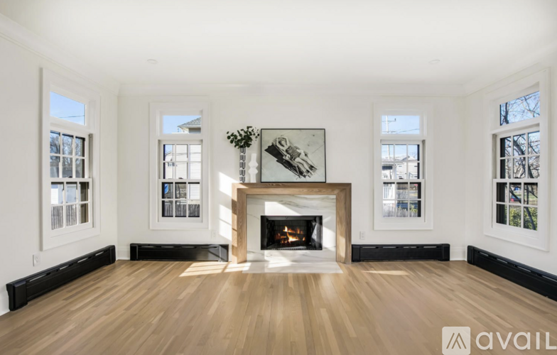 A large, empty room with a fireplace and wooden floors.