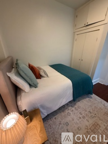A bedroom with a bed, a lamp, and a cabinet.
