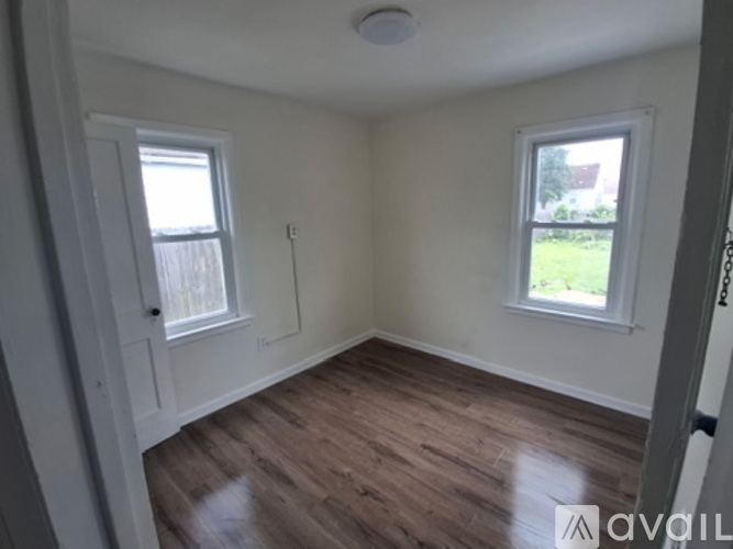 A room with wooden floors and two windows.