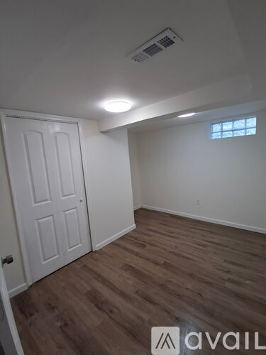 A room with a white door and a window with a white wall and wooden floor.