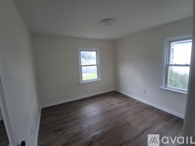 A room with wooden floors and two windows.