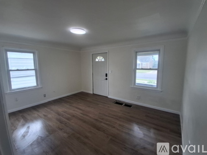 A room with wooden flooring and a door in the middle.