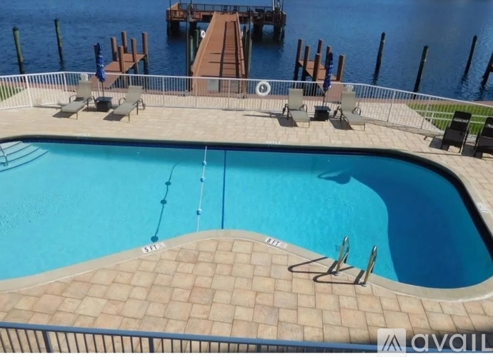 A pool with a brown tile floor and a metal railing.