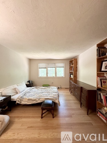 A bedroom with a bed, a chair, and a bookshelf.