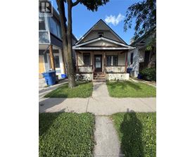 A house with a porch and a tree in front of it.