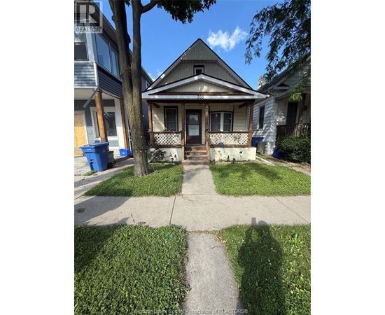 A house with a porch and a tree in front of it.