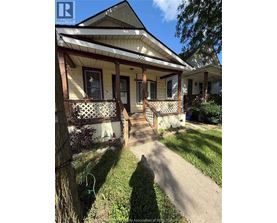 A house with a porch and a tree in front of it.